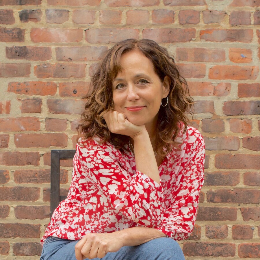 laura from the book doctors posing in front of a brick wall, seated